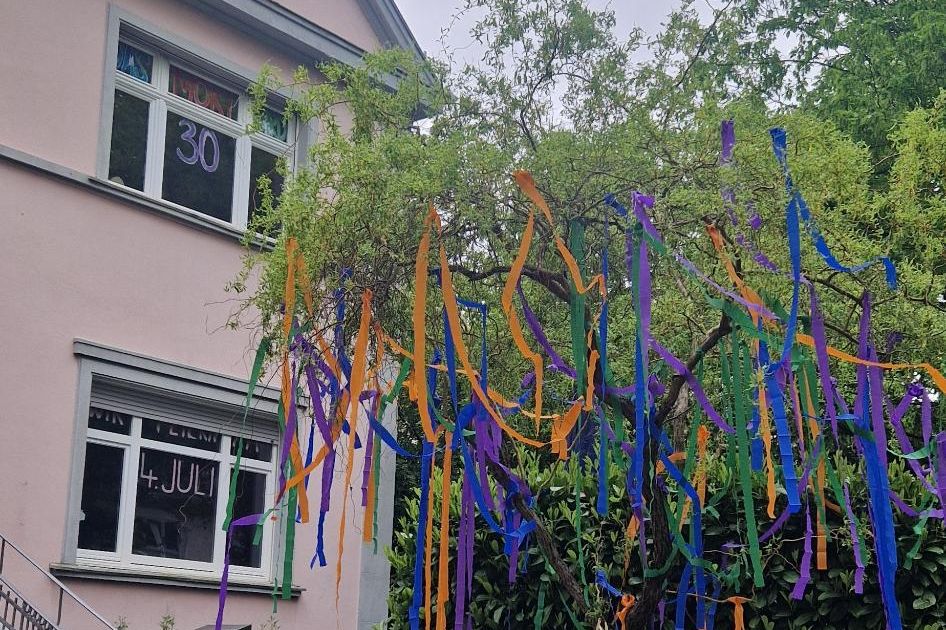 Die Villa zum Sommerfest: ein Baum voller bunter Bänder, im Fenster eine große „30“