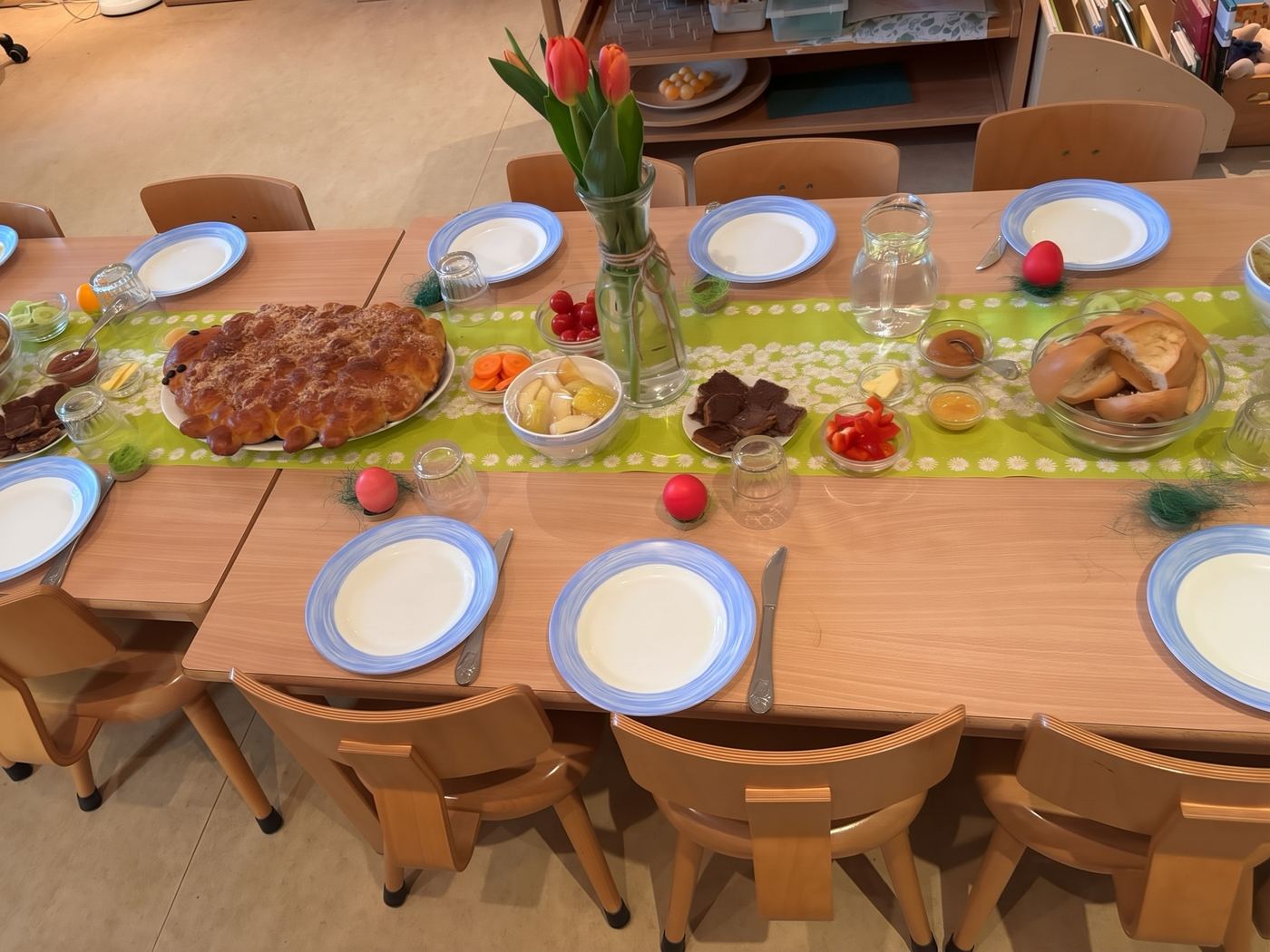 Festlich gedeckter Tisch beim Osterfrühstück mit Hefezopf, Obst, Gemüse und Tulpen