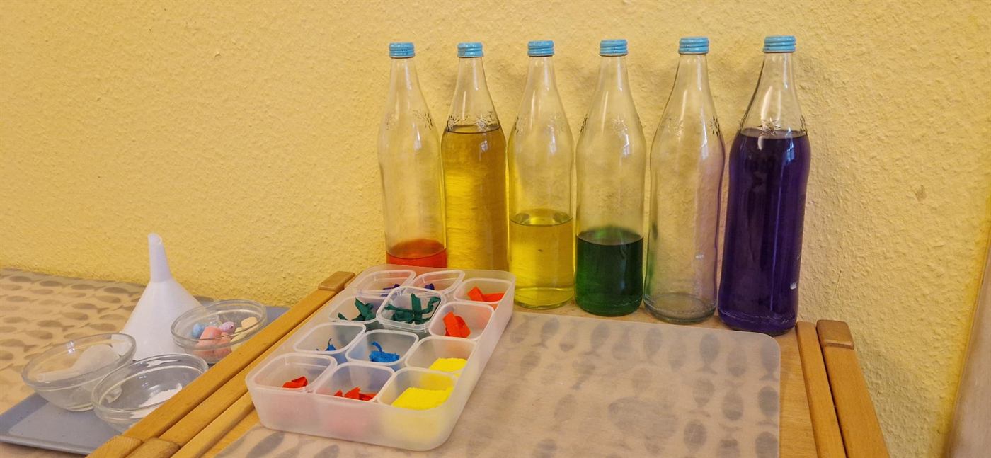 Flaschen mit gefärbtem Wasser und Material zum Farbenmischen