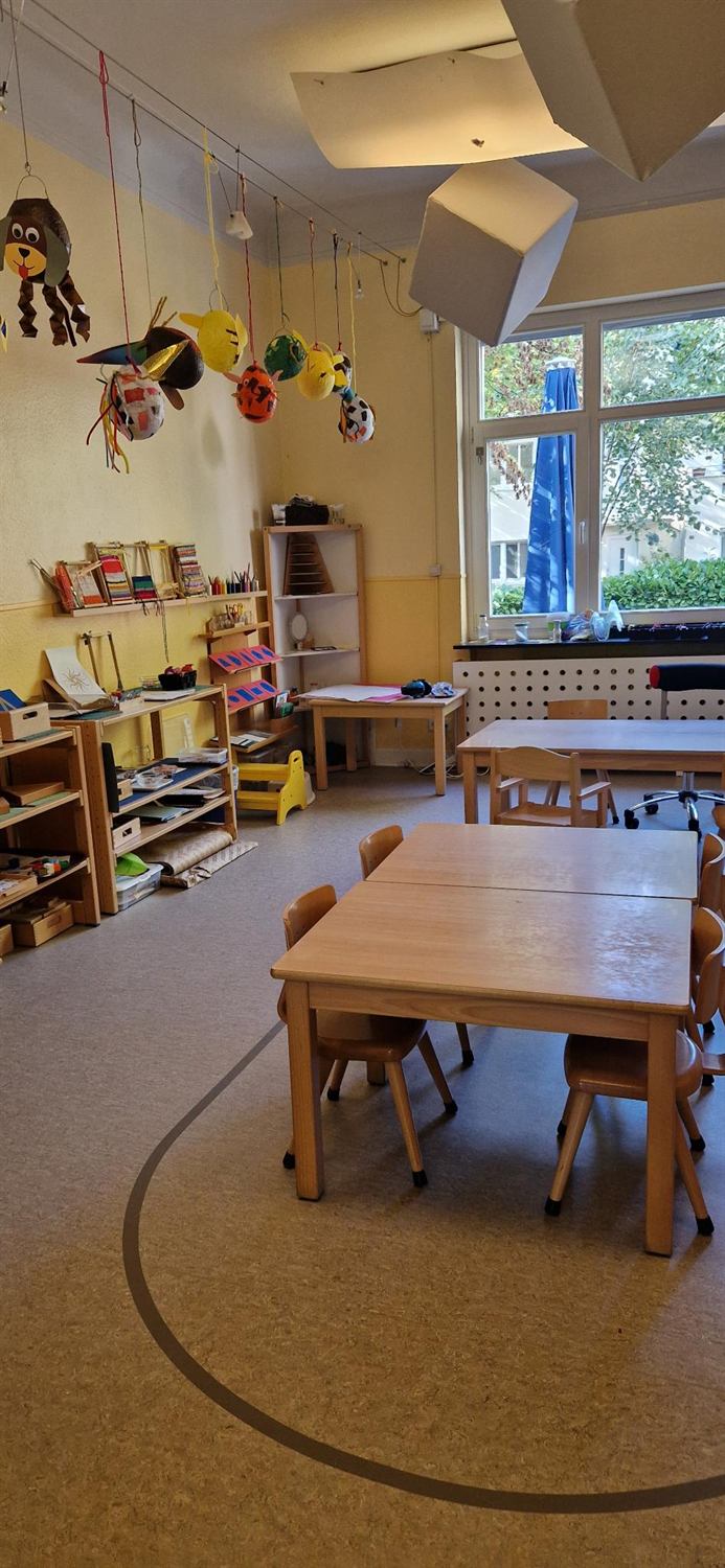Gruppenraum mit Regalen voller Montessori-Material und Kindertischen
