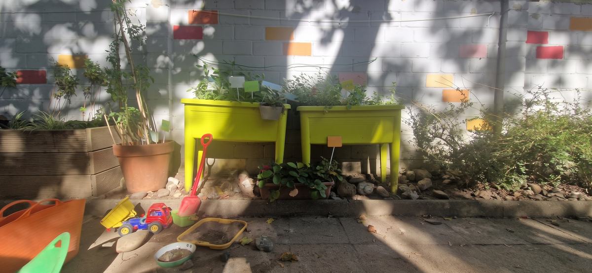 Hochbeete und Sandspielzeug an der bunten Gartenmauer