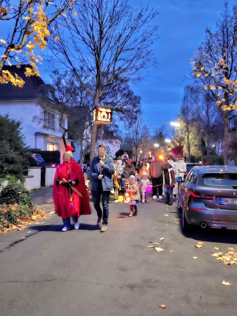 Der St.-Martins-Umzug zieht in der Abenddämmerung mit Laternen durch die Straße
